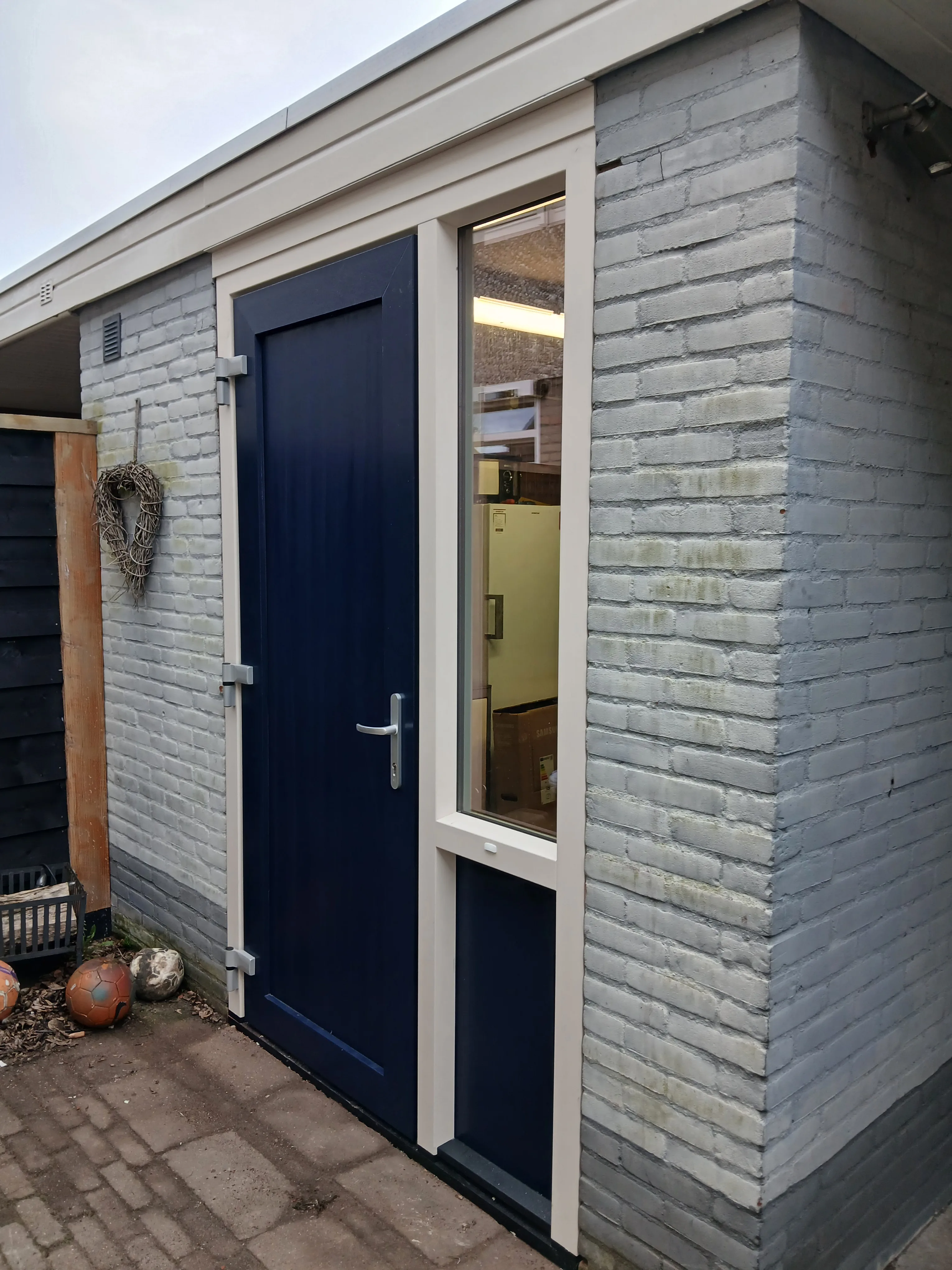 Grijze voorgevel met donkerblauwe deur en raam