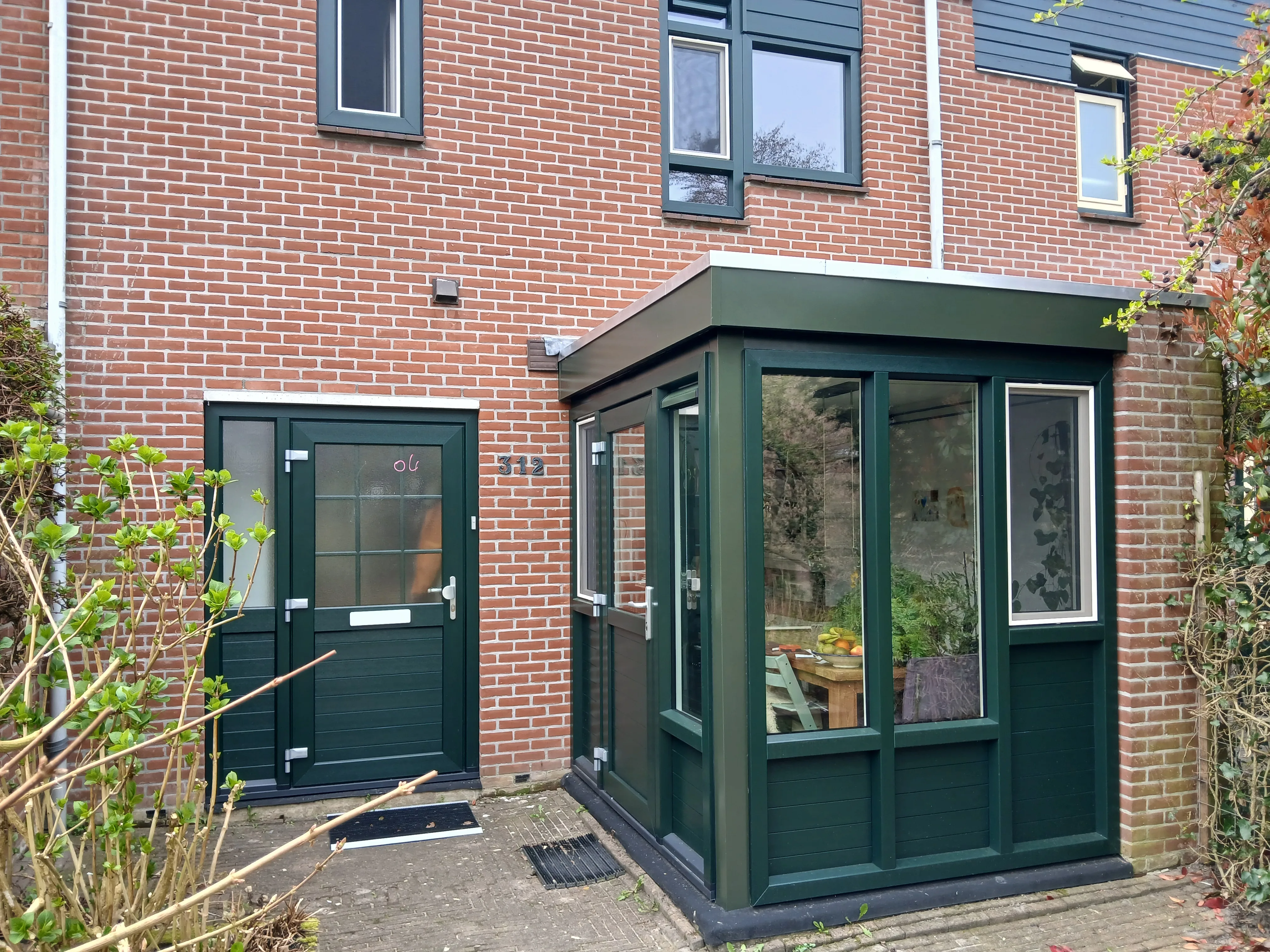 Groene houten entree aan bakstenen huis