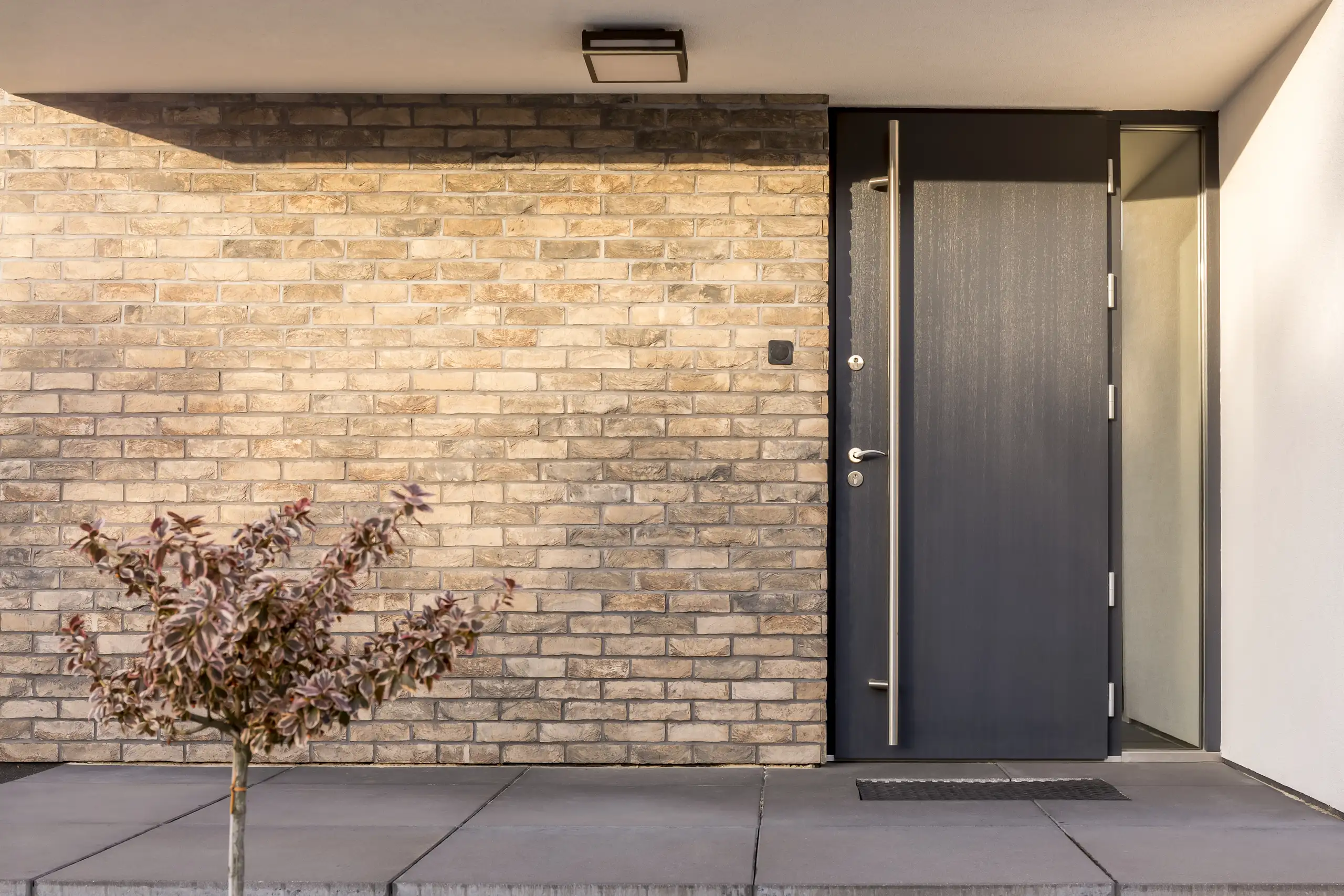 Moderne voordeur met strakke lijnen en mooie steenwand, perfect voor een uitstraling van kwaliteit