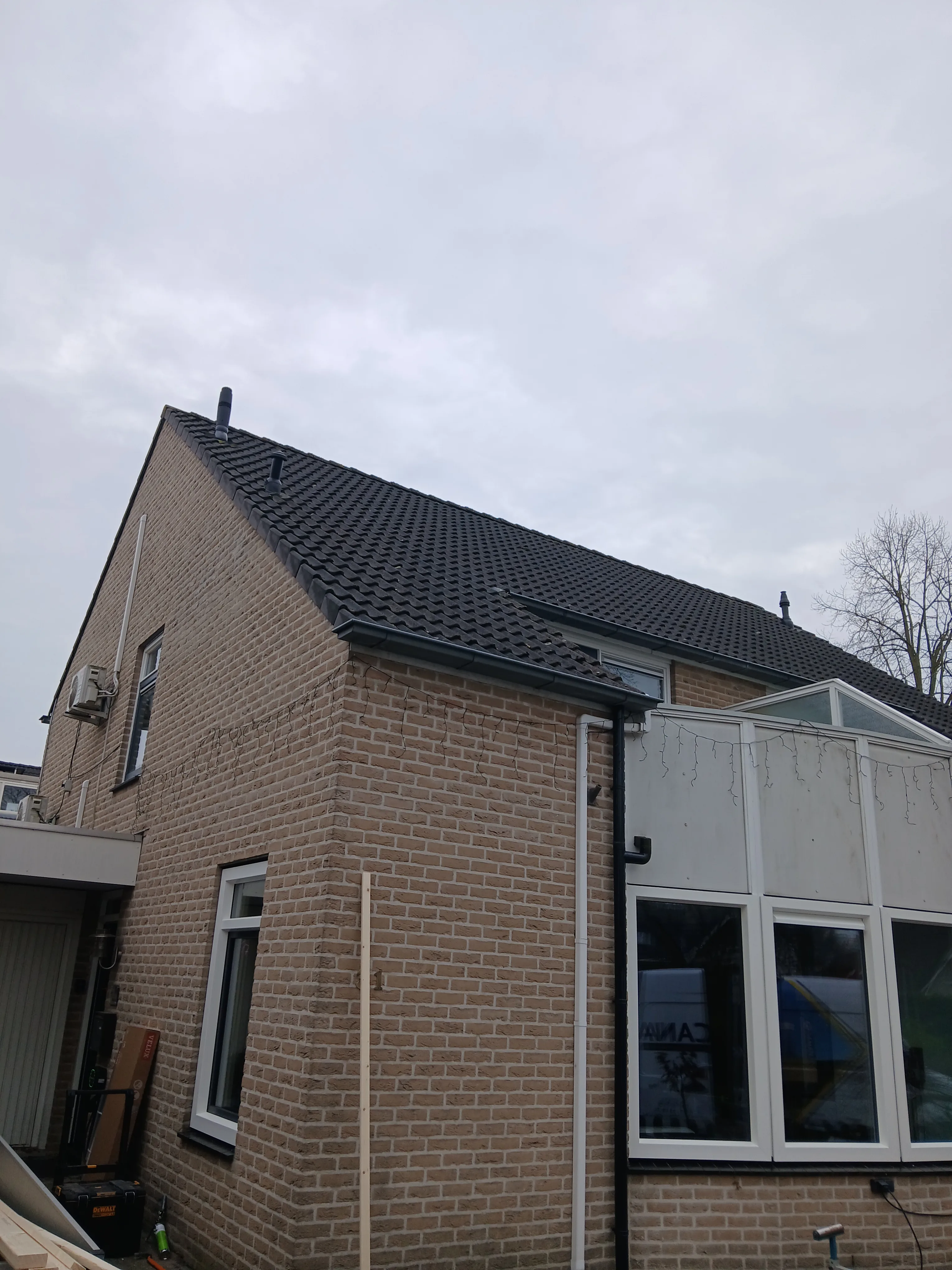 Een van de zijkanten van een woning met kunststof kozijnen en een dakkapel