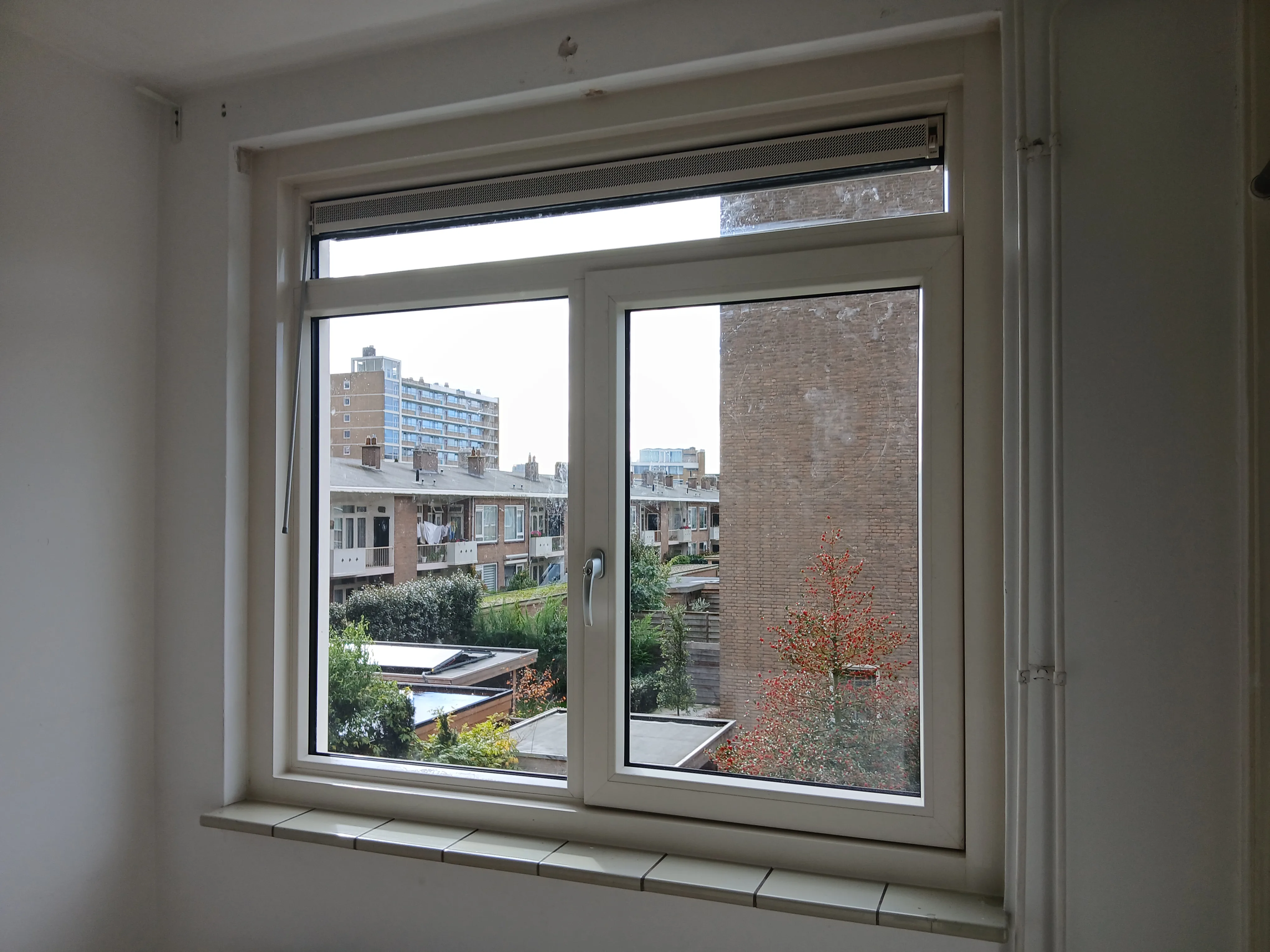 Kunststof kozijnen vanuit een raam met uitzicht op een stadslandschap