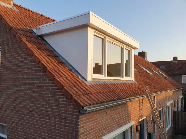 Dakkapel op maat met kunststof gevelbekleding op een schuin dak in de avondzon