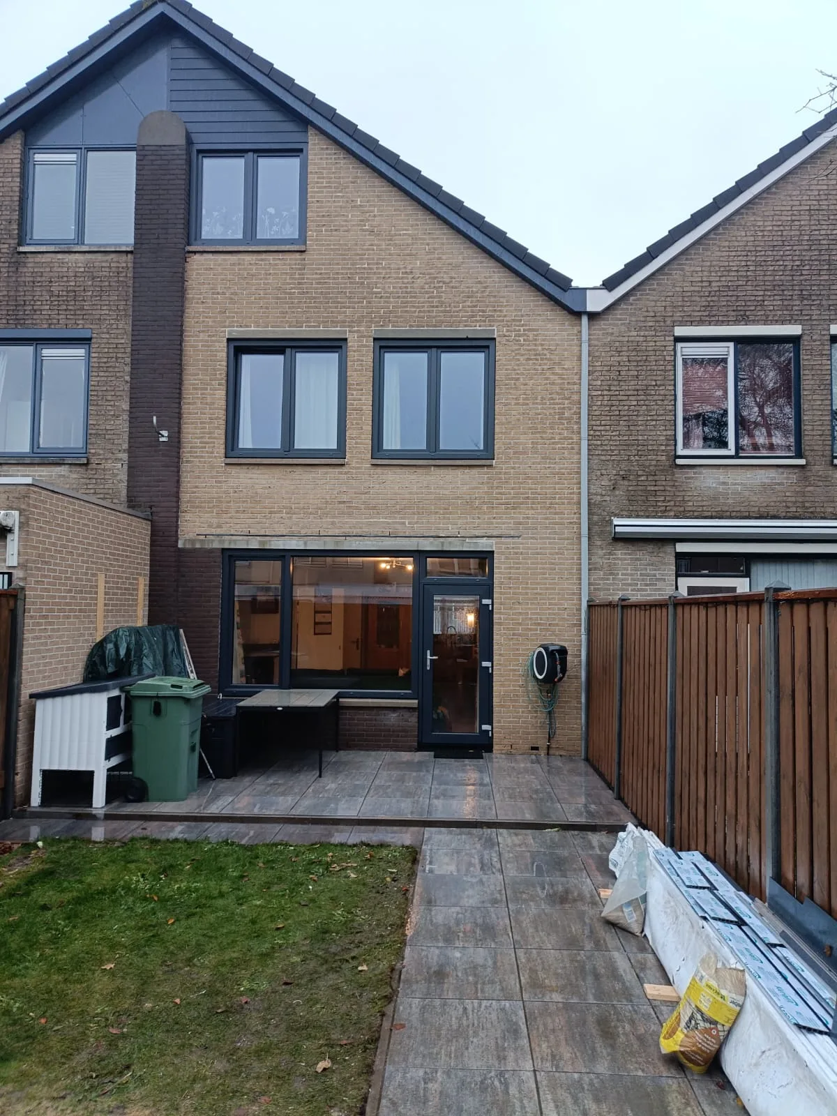 Achtertuin met houten schutting en kunststof schuifpui van een woning