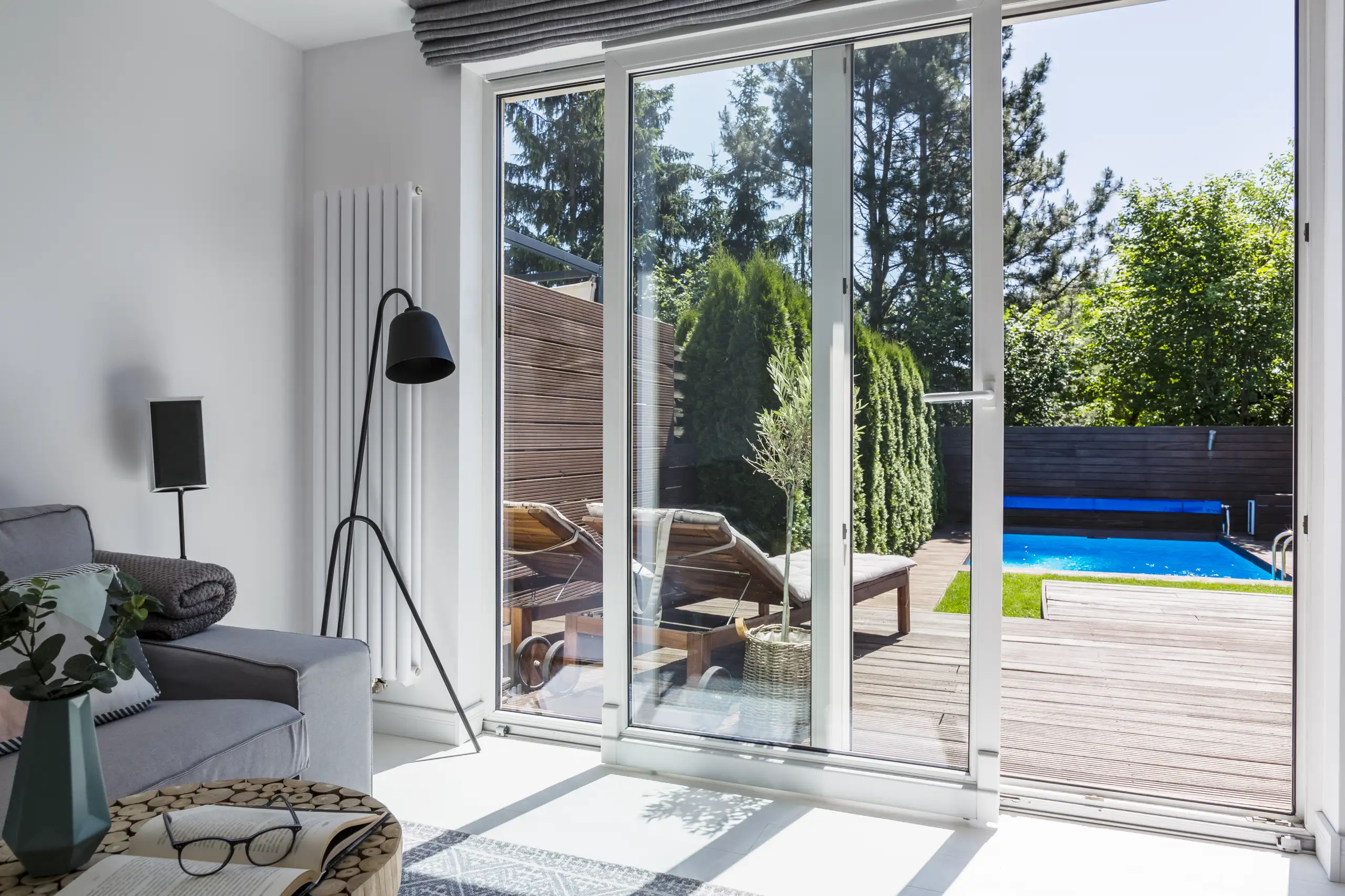 Moderne kunststof schuifpui met uitzicht op een groene tuin en zwembad