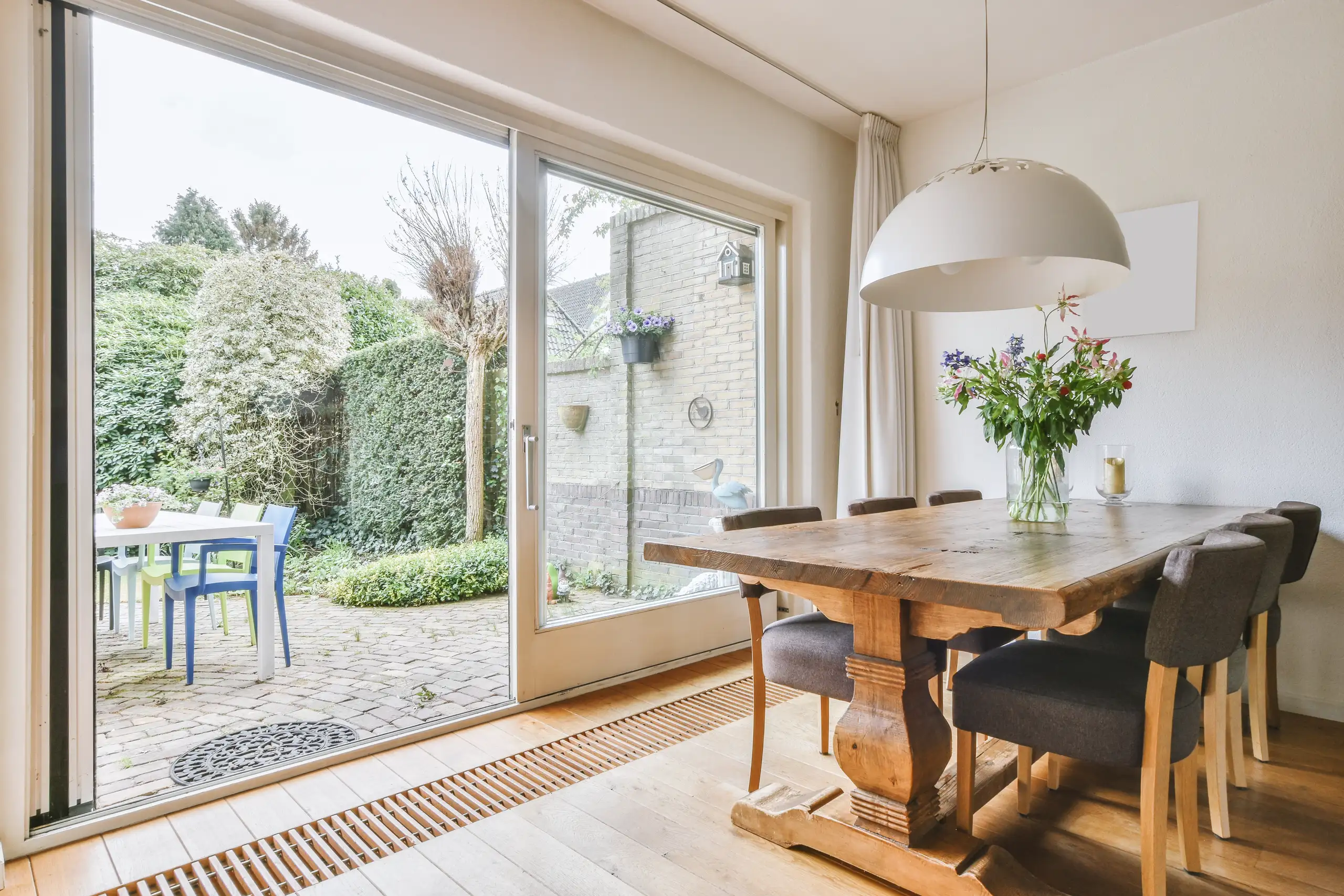 Interieur van een eetkamer met houten tafel en toegang tot de tuin via een schuifpui